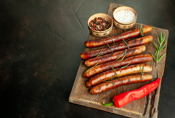 Grilled sausages with spices and rosemary on a stone table