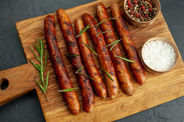 Grilled sausages with spices and rosemary on a stone table