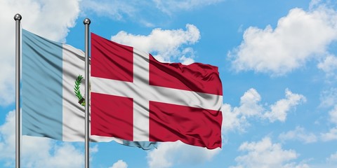 Guatemala and Denmark flag waving in the wind against white cloudy blue sky together. Diplomacy...