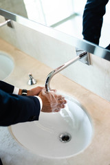 high angle view of man washing hands in public bathroom