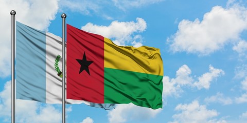 Guatemala and Guinea Bissau flag waving in the wind against white cloudy blue sky together. Diplomacy concept, international relations.