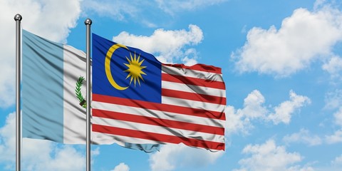 Guatemala and Malaysia flag waving in the wind against white cloudy blue sky together. Diplomacy concept, international relations.