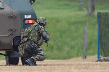 装甲車の陰で銃を構える自衛官