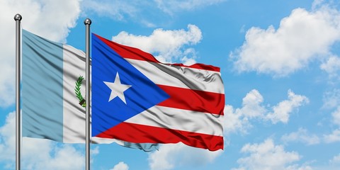 Guatemala and Puerto Rico flag waving in the wind against white cloudy blue sky together. Diplomacy...