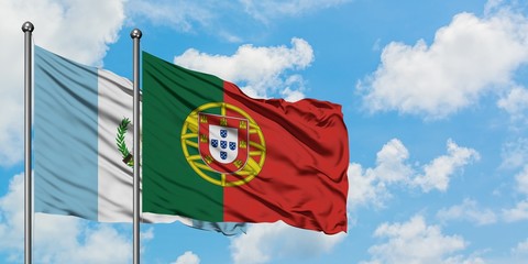 Guatemala and Portugal flag waving in the wind against white cloudy blue sky together. Diplomacy...