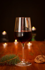 Glass of wine on wooden table with some lights in background. Christmas cheers.