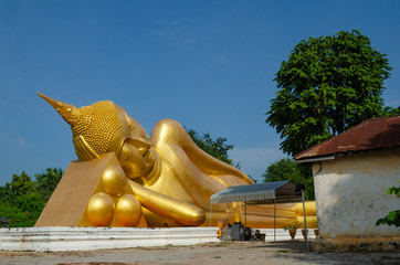Reclining Buddha gold statue ( Phra Buddhasaiyas ) with blue sky