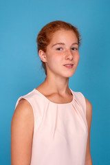 Studio shot of a attractive girl teenager with red hair  against  blue background