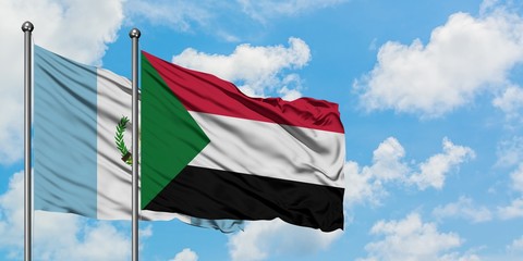 Guatemala and Sudan flag waving in the wind against white cloudy blue sky together. Diplomacy...