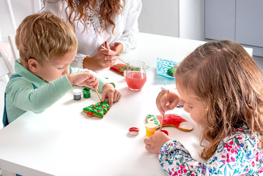 Little children with a nanny  to prepare for Christmas.  They sit at the table in the room