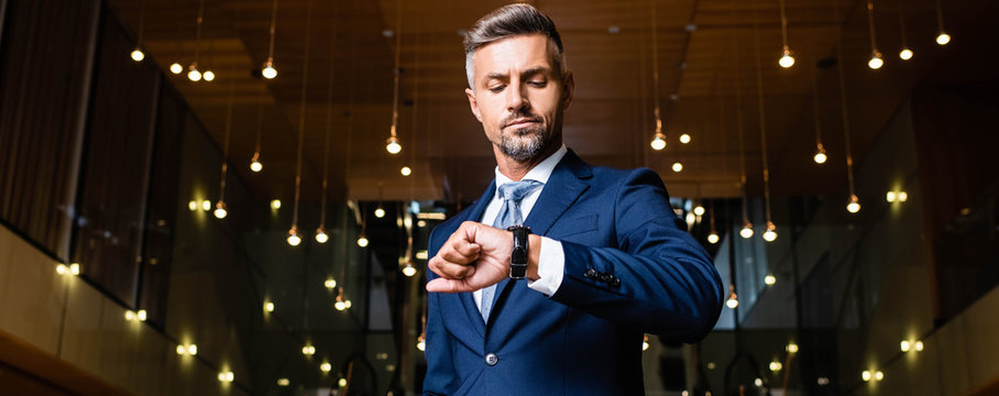 panoramic shot of businessman in suit looking at watch