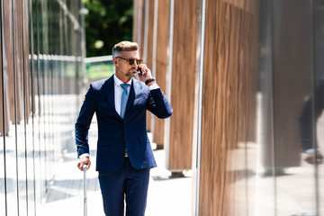 handsome businessman in suit and glasses talking on smartphone