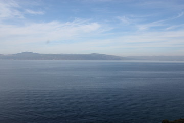 Blue sea and mountain landscape. Blue sky and fluffy clouds landscape.