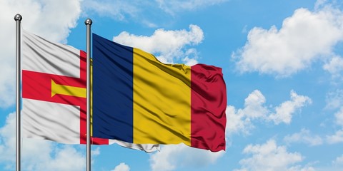 Guernsey and Chad flag waving in the wind against white cloudy blue sky together. Diplomacy...