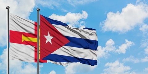 Guernsey and Cuba flag waving in the wind against white cloudy blue sky together. Diplomacy concept, international relations.