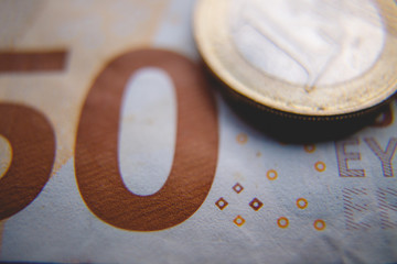 Macro photo of a coin in 1 Euro on a blurred background banknote in 50 euro. Money background. Extremely small depth of field.