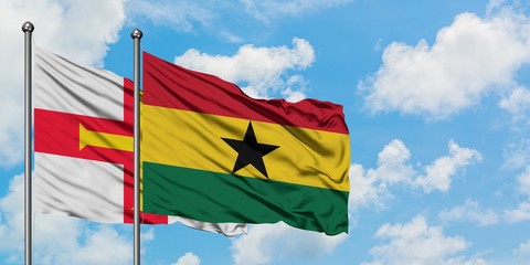 Guernsey and Ghana flag waving in the wind against white cloudy blue sky together. Diplomacy concept, international relations.