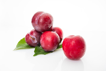 red  plum with green leaves isolated on white background