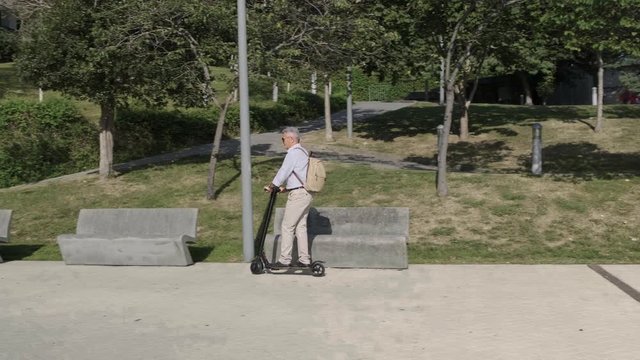 Senior man riding on electric scooter in a park