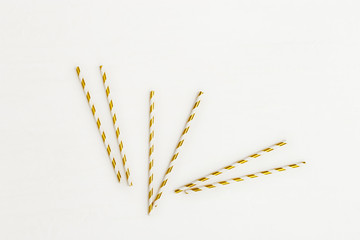 Colorful paper cocktail straws with striped pattern gold colored for Birthday or holiday. Celebration creative background. View from above.
