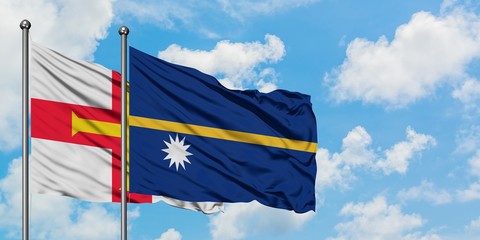 Guernsey and Nauru flag waving in the wind against white cloudy blue sky together. Diplomacy...