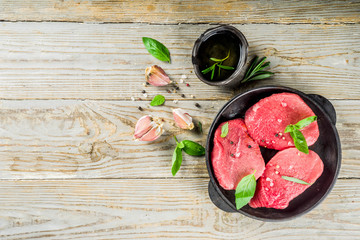 Raw fresh meat. Beef meat steaks with spices and herbs, wooden background top view copy space