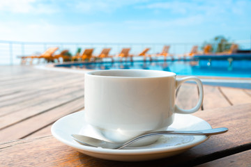 cup on the table near the pool . White ceramic coffee cup
