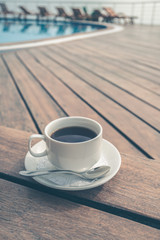 cup on the table near the pool . White ceramic coffee cup