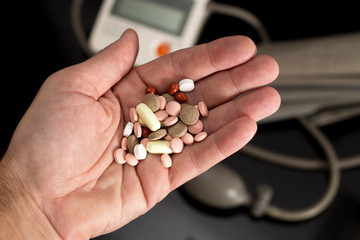 Bunch of drugs in the palm and digital blood pressure monitor