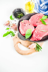 Raw fresh meat. Beef meat steaks with spices and herbs, white background top view copy space