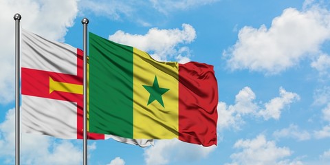 Guernsey and Senegal flag waving in the wind against white cloudy blue sky together. Diplomacy concept, international relations.