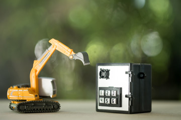 Miniature safe deposit with a code lock and excavator model toy. © Dontree