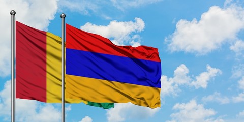 Guinea and Armenia flag waving in the wind against white cloudy blue sky together. Diplomacy...
