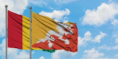 Guinea and Bhutan flag waving in the wind against white cloudy blue sky together. Diplomacy...