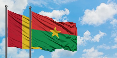 Guinea and Burkina Faso flag waving in the wind against white cloudy blue sky together. Diplomacy...