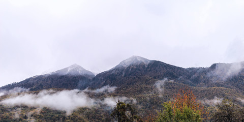 Fog in the mountains against the background of peaks with snow in the fall in Sochi, Russia.