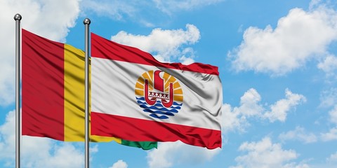 Guinea and French Polynesia flag waving in the wind against white cloudy blue sky together. Diplomacy concept, international relations.