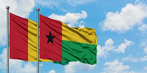 Guinea and Guinea Bissau flag waving in the wind against white cloudy blue sky together. Diplomacy concept, international relations.