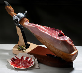 jamón de bellota, y plato con jamón cortado sobre fondo negro. acorn-fed ham, and a plate with...
