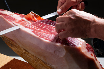 jamón serrano, manos cortándolo con cuchillo. Serrano ham, hands cutting it with a knife. - obrazy, fototapety, plakaty