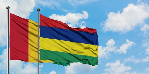 Guinea and Mauritius flag waving in the wind against white cloudy blue sky together. Diplomacy concept, international relations.