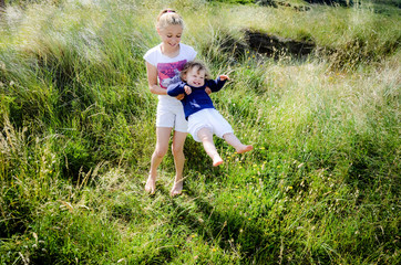 two pretty sisters playing together in tall grass