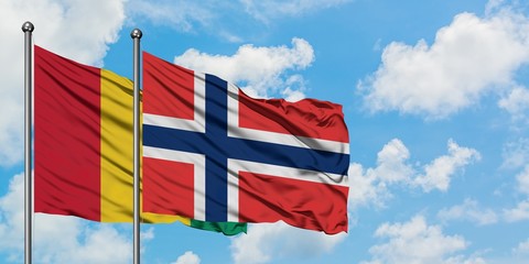 Guinea and Norway flag waving in the wind against white cloudy blue sky together. Diplomacy concept, international relations.