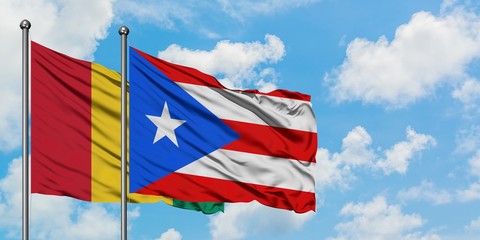 Guinea and Puerto Rico flag waving in the wind against white cloudy blue sky together. Diplomacy concept, international relations.