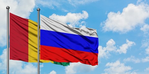Guinea and Russia flag waving in the wind against white cloudy blue sky together. Diplomacy concept, international relations.