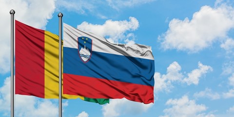 Guinea and Slovenia flag waving in the wind against white cloudy blue sky together. Diplomacy concept, international relations.