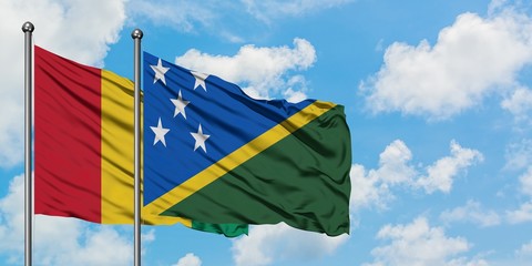 Guinea and Solomon Islands flag waving in the wind against white cloudy blue sky together. Diplomacy concept, international relations.