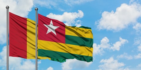 Guinea and Togo flag waving in the wind against white cloudy blue sky together. Diplomacy concept, international relations.