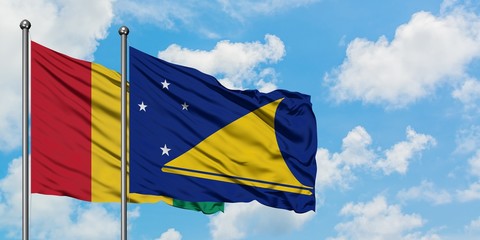 Guinea and Tokelau flag waving in the wind against white cloudy blue sky together. Diplomacy concept, international relations.