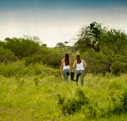 Young female sisters walk in the field, looking for the horses to ride